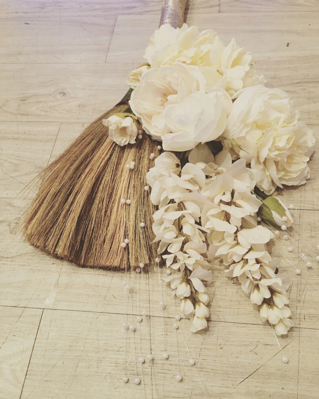 A decorated ceremonial broom dressed with white flowers
